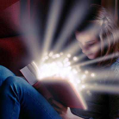 Una chica leyendo un libro que emana luz