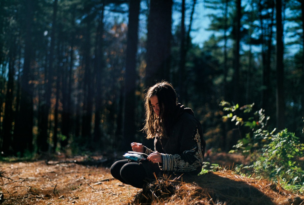 una chica sentada a leer en un bosque